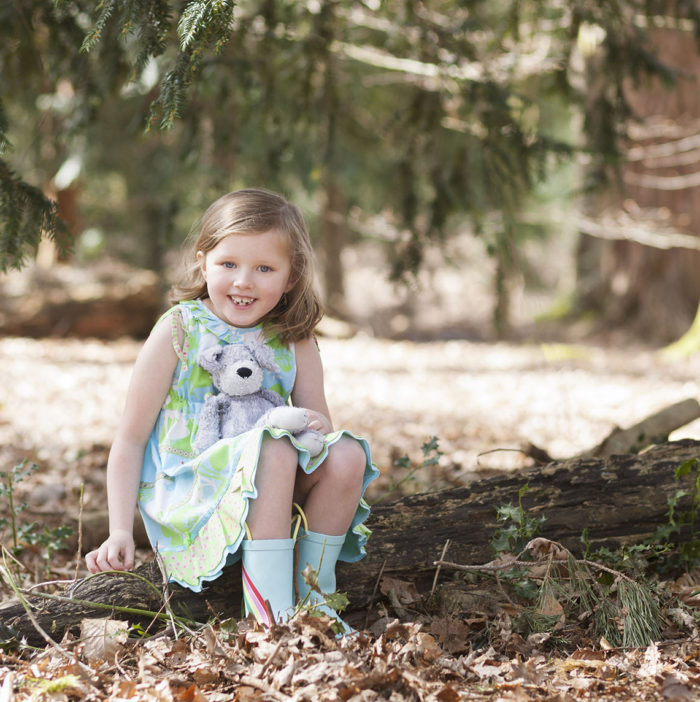 Girl with teddy bear sat on a log during Spring mini shoot in Styal Woods in Manchester