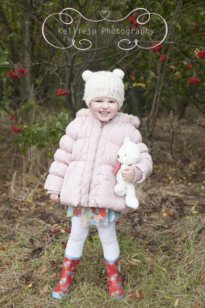 Cheshire and Manchester Children photographer in Autumn holding her teddy near some berries.