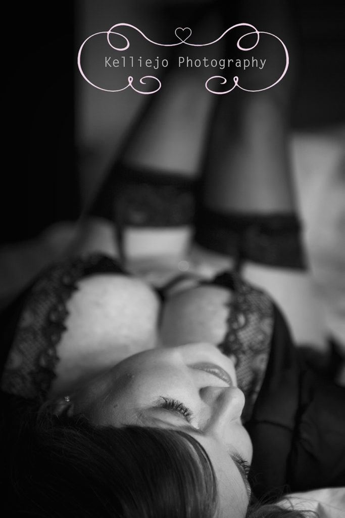Cheshire and Manchester Boudoir photography of a black and white photograph of a lady in black lingerie lay on a bed.