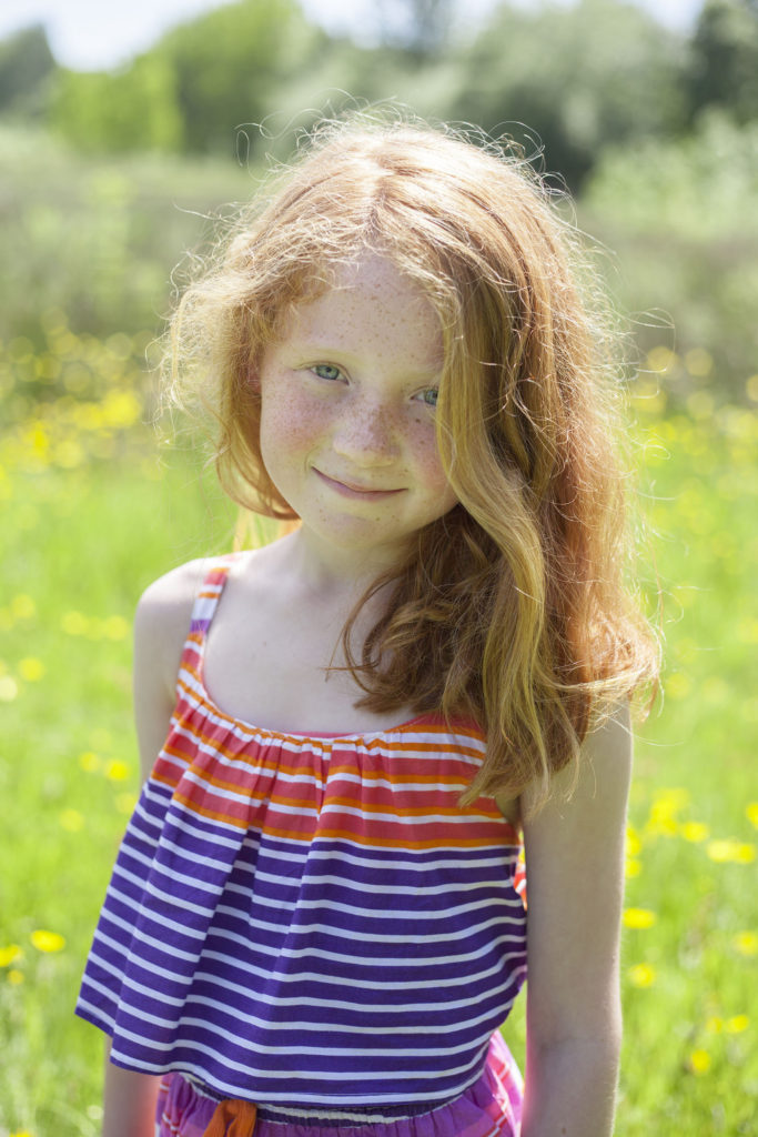 Cheshire children's photography of a ginger haired little girl in a field at Abney Hall Park.