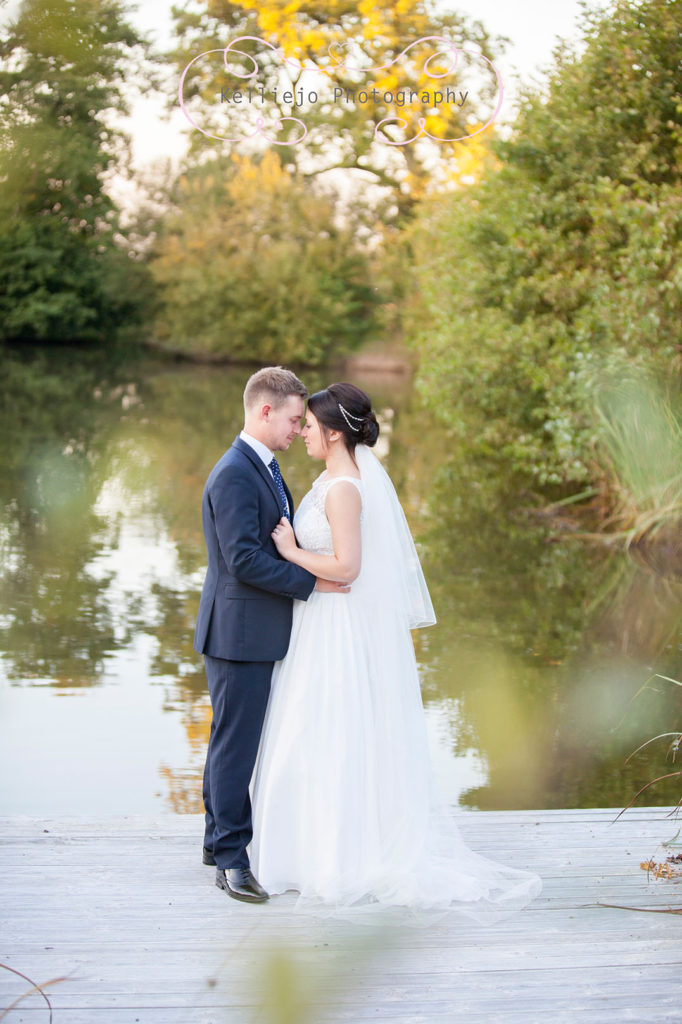 Cheshire wedding photography of a bride and groom by the lake at Styal Lodge wedding venue.