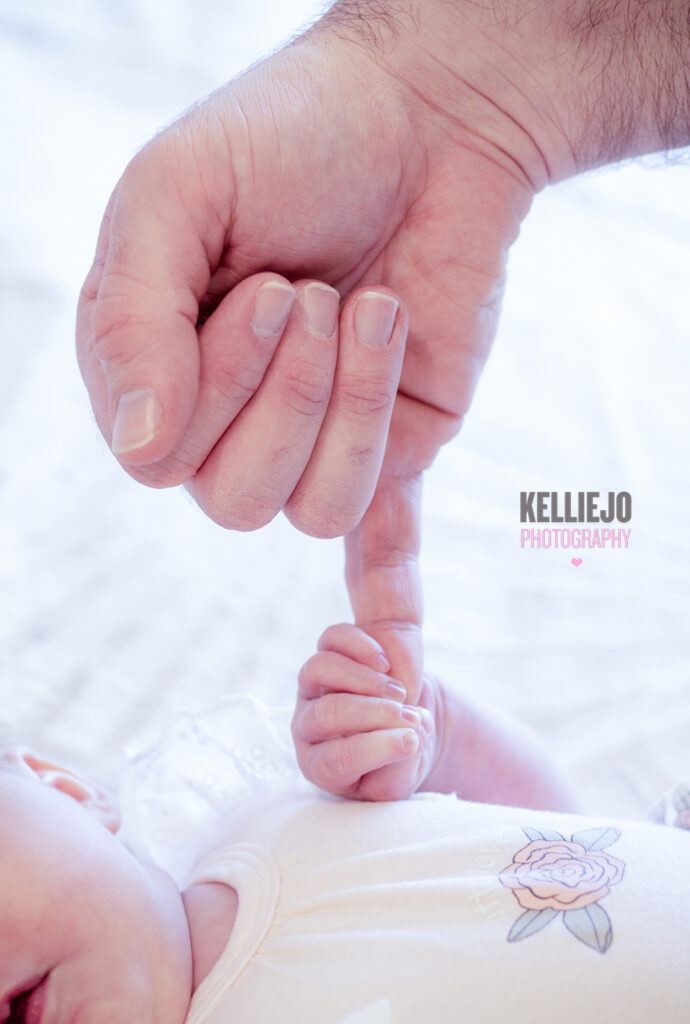baby holding daddy's finger during a newborn photography at home